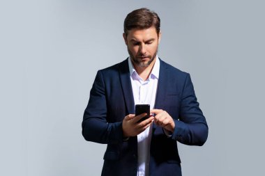 Takım elbiseli bir iş adamı telefonda konuşuyor. Promosyon mobil uygulaması. Stüdyonun arka planında izole edilmiş akıllı telefon kullanan sıradan giyinmiş bir iş adamı. Cep telefonu kullanan, sosyal medyayı karıştıran neşeli adamın portresi