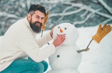 Komik kardan adamlar. Mutlu gülümseyen adam güneşli kış gününde kardan adam olun. Kardaki insanlar. Snowman. Soğuk kış Parkı'nda kardan adam ile Yakışıklı Kış Adam
