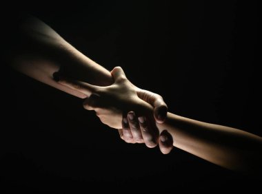 İki eğilim ve iki eğilim. Bir arkadaşa yardım ediyorum. Kurtarmak ya da el hareketlerine yardım etmek. Kurtuluş kavramı. Kurtarma sırasında iki güçlü insanın elleri, yardım edin. Siyah arkaplanda izole