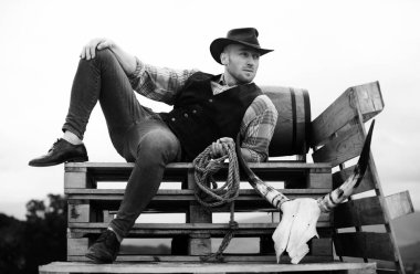 Erkek kovboy. Çiftliğin sahibi. Çiftlik işçisi ve tarım kavramı. Kovboy şapkalı ve köylü tarzı kıyafetli yakışıklı bir adam. Erkekler eski moda, eski moda, vahşi erkek model.