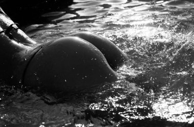 Woman sexy swimwear. Sexy womans body. Closeup beautiful hot female buttocks, perfect body shape, firm butt. Tanned skin of bikini model. Hips big natural butt in swimming pool. Hot summer
