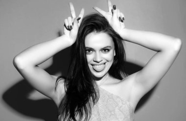 Genç bir kadın boynuzları gibi parmaklarıyla komik jestler yapıyor. Çılgın komik seksi kız boynuzları gibi parmaklarıyla komik jestler yapıyor. Boynuzlarını gösteren kadın