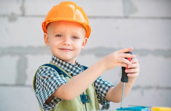 Child in building helmet, hard hat. Child dressed as a workman builder. Portrait happy smiling little builder in hardhats. Little builder in helmet