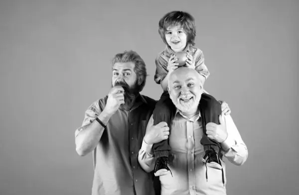 Grandfather father and grand son hugging and eating apple. Men in different ages, isolated on yellow