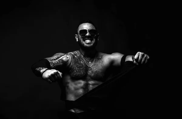 Furious man isolated on black. Topless shirtless male model ripped shirt