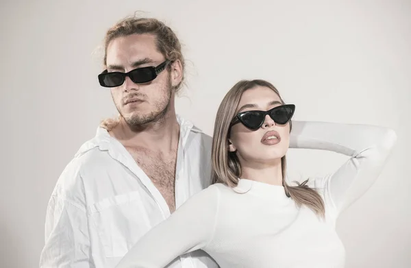 Couple in fashion black sunglasses. Young couple posing with sunglasses. Studio shot on gray background