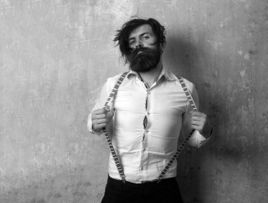 Komik deli adam pantolon askısı samimi bir yüz ifadesi takınıyor. Taranmamış dağınık saçlı sakallı adam.