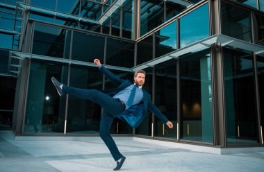 İş heyecanı. İş adamı kollarını havada tutuyor ve dışarıda pozitifliğini gösteriyor. Başarılı bir kutlama için sevinçten zıplayan iş adamı.