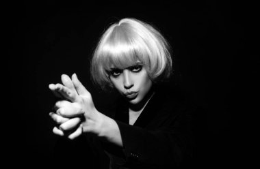 Ateş eden parmaklar. Kadınların el yapımı ateşli silah, jest. El tabancası hareketi. Pembe peruklu güzel seksi kadın, siyah giyinmiş.