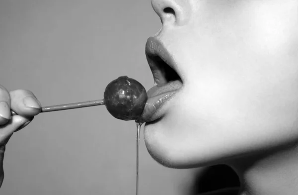 Sexy blow jobs symbol. Licking candy. Lollipop model. Woman lips sucking a candy. Oral sex blow job concept. Glamor sexy model with red lips eat sweats lolly pop