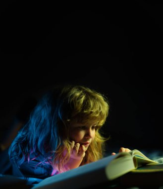 Çocuk yatakta sihirli bir kitap okuyor. Çocuk evde kitap okurdu. Eğitim ve okuma kavramı