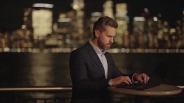 Gece New York 'ta Ciddi İş Adamı. Olgun adam dışarıda dizüstü bilgisayarda çalışıyor. Gece Sokağındaki İşadamı. İspanyol ofis çalışanı. Gece şehir dışında dizüstü bilgisayar kullanan bir iş adamı.