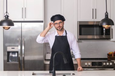 Aşçı şapkalı adam mutfakta yemek pişiriyor.