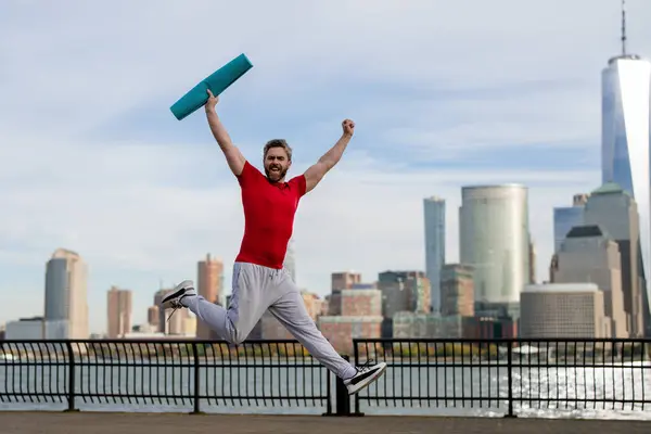 Man in fitness wear exercising near Manhattan. Healthy exercises. Active senior man is fitness exercising outdoor. Exercising after retirement. Mature retired sportsman doing stretching exercises