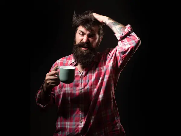 Mans holds cup of coffee and yawning. Morning tea. Yawning face. Man with tea cup. Hipster man yawning with cup of coffee. Bearded man yawning hold mug tea. Wake up. Happy day. After morning tea
