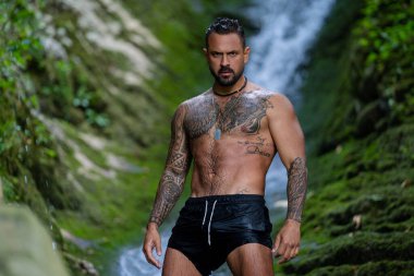 Şelalenin yanındaki adam. İnsan özgürlüğü yaşam tarzı. Doğadaki turizm. İspanyol turist. Yaşam tarzı rahatlama konsepti, yaz seyahati. Şelalenin altındaki çıplak adam sıçramanın keyfini çıkarıyor.