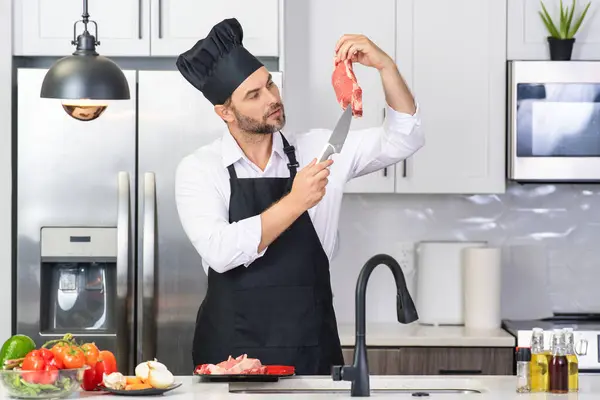 Aşçı mutfakta sebzelerle yemek pişiriyor. Sağlıklı yemek. Mutfakta yemek pişiren çekici beyaz adam. Modern mutfakta sağlıklı yemek pişiren adam. Şef mutfakta yemek hazırlıyor.