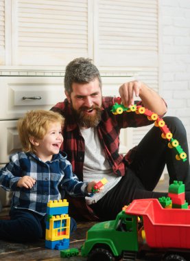 Baba ve oğul tuğladan oyuncak yaparlar. Baba ve çocuk plastik bloklardan inşa edilmiş. Mutlu aile, babalar günü