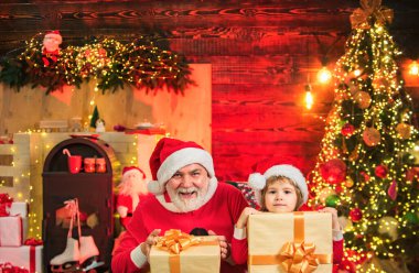 Hediyelerle dolu bir çanta taşıyan komik küçük Noel baba ve oğul. Noel Baba çocuk büyükbaba ve torun. Çocuk Noel ağacının yanında gerçek Noel Baba 'yla oynuyor.