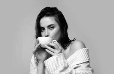 Bornozlu bir kadın model elinde bir fincan kahve tutuyor. Kahve fincanı ile gülümseyen mutlu kadın, stüdyo izole