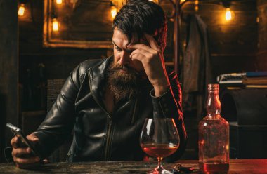 Yakışıklı sakallı iş adamı pahalı bir viski içiyor. Sosyal medya bağımlılığı, alkol bağımlılığı