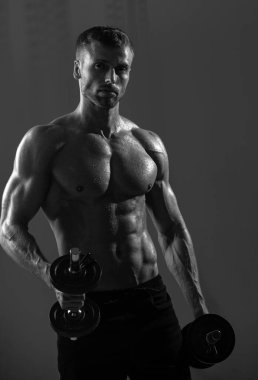 Seksi spor gövdesi, dambılı adam. Güçlü kaslı adam. Antrenman yaşam tarzı konsepti. Fonksiyonel antrenman yapan yakışıklı adam.