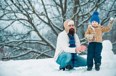 Happy father and son play on winter Christmas time. Fathers day. Happy child playing with snowball against white winter background. Happy loving family