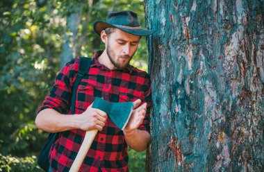 Oduncu işçi ormanda baltayla yürüyor. Ormanların tahrip edilmesi doğal ekosistemlerin bozulması ve istikrarsızlaşmasının başlıca nedenlerinden biridir.