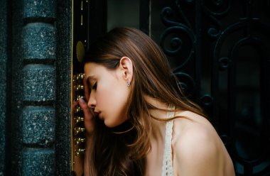 Depresyondaki üzgün kadın. Kendini soyutlama. Ev güvenliği kavramı. Kadın dahili iletişim kodu düğmesi. Bayan kadın kapı zili bina girişinde.