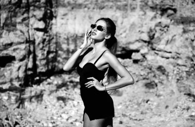 Modayı takip eden güneş gözlüklü ve moda siyah elbiseli bir kadın. Moda kıyafeti giymiş çekici bir kadın. Baharın tadını çıkaran güzel bir bayanın açık hava moda fotoğrafı.