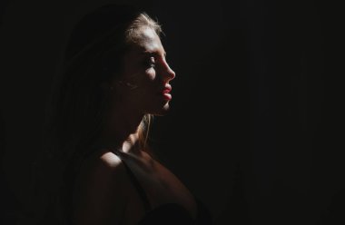 Siyah stüdyoda gölgeli, güzel yüzlü seksi bir kadın. Şehvetli kız.