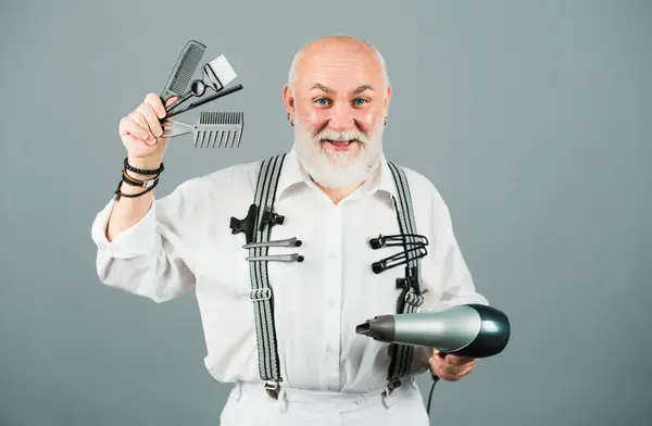 stock image Senior bearded man, bearded old male. Portrait of vintage barber. Barber scissors and straight razor, hair dryer in barbershop. Retro barbershop, shaving. Hair dresser