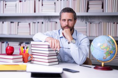 Kütüphanede kitabı olan bir öğretmenin portresi. Üniversitede yakışıklı bir öğretmen. Öğretmenler Günü. İyi bir öğretmen. Üniversitede öğretmen. Kütüphanede kitapları olan bir adam. Bilgi ve eğitim kavramı