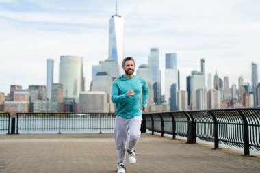 Kaçak adam. Sağlıklı spor. New York 'ta koşan adam. Fitness koşucusu Manhattan yakınlarında koşuyor. Amerikan caddesinde koşan adam. Spor kıyafetlerle New York 'ta koşan bir adam. Koşucular için spor kıyafeti