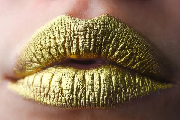 Close up woma face with gold lips. Gold paint on mouth. Golden lips. Luxury gold lips make-up. Golden lips with creative metallic lipstick. Gold metal lip. Sensual woman mouth, clse up, macro
