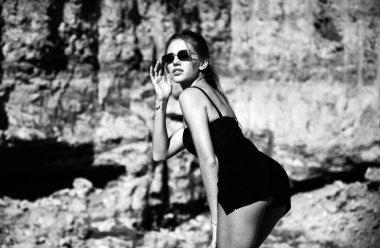 Modayı takip eden güneş gözlüklü ve moda siyah elbiseli bir kadın. Dışarıdaki moda elbiseli kadın manken.