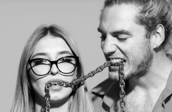 Fashionable young people. Couple with chains in mouth