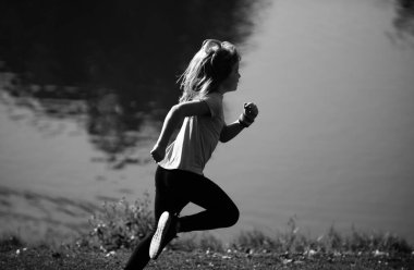 Çocuk koşucular parkta koşar. Sportif genç çocuk koşuyor ve dışarıda antrenman yapıyor. Aktif enerjik çocukluk