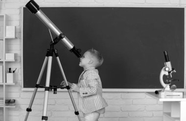 School boy with telescope learning astronomy lesson at school