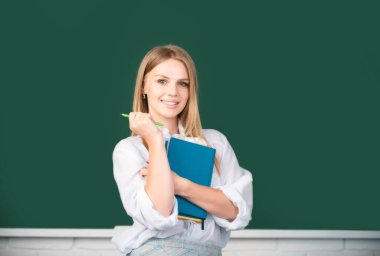 Üniversitede ya da okulda bayan üniversite öğrencisinin portresi. Kalem ve kitapla gülümseyen yaratıcı genç bayan öğrenci.