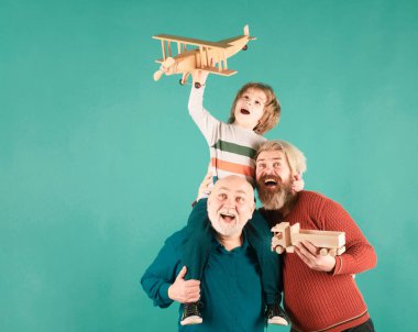 Üç farklı nesil, büyükbaba ve oğul stüdyoda oyuncak uçakla oynuyorlar. Seyahat konsepti. İzole edilmiş arka plan. Aile macerası, yenilik ilhamı