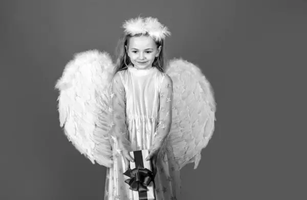 小女孩天使礼物 工作室肖像 白色翅膀的小天使带着礼物 可爱的天使小女孩 长着天使般的翅膀 与红色隔离 情人节礼物卡 — 图库照片