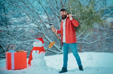 Adam bir Noel ağacı kesecek. Kış hissi. Ormanda noel ağacını yeni kesilmiş sakallı adam. Mutlu kış zamanı. Mutlu Noeller ve Mutlu Tatiller