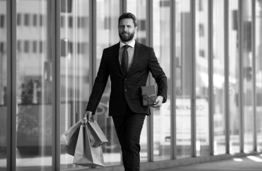 Alışveriş torbaları tutan ve alışveriş mağazasında yürüyen bir iş adamı. Alışveriş ve ödeme. Alışverişkolik alışveriş kavramı