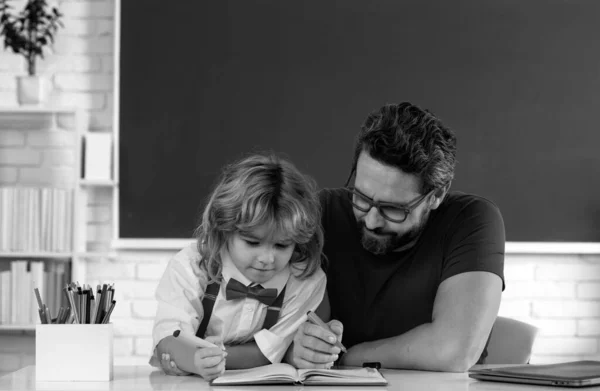 子供の男の子は先生と勉強する 黒板の授業で父親と一緒に面白い男の子の勉強 小学生の子供 レッスンの教室にいる小学生 弟子への説明 — ストック写真