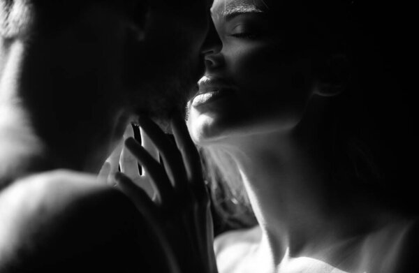 Sensual woman lips in the tender passion. Romantic couple in love looking at each other, embracing and kissing on black background