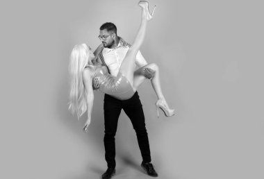 Sevgililer Günü. Yaratıcı bebekler çift konsepti. Komik adam kadını kollarına alıp kucaklıyor. Birbirine aşık bir çift. Yakışıklı adam pembe arka planda pembe elbiseli güzel kız arkadaşına sarılıyor.