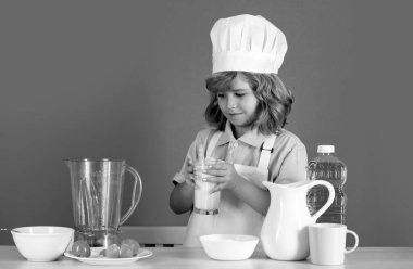 Yemek pişiren çocuklar. Aşçı çocuk sağlıklı yemek için taze sebze yapıyor. Mavi arka planda izole edilmiş küçük çocuk portresi. Aşçı çocuk. Yemek pişirme süreci