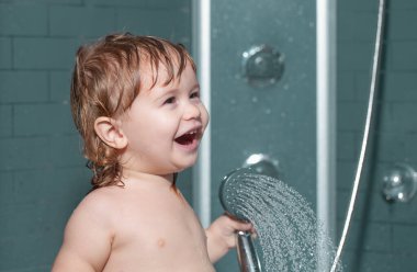 Duşun altında yıkanan çocuk. Küçük bebek saçını banyoda yıkıyor.