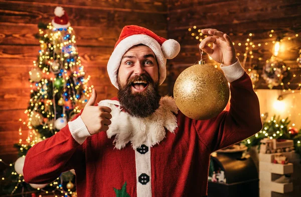 Crazy, funny Hipster Santa. Portrait of happy Santa with decorative toy balls near Christmas tree. Happy Santa dressed in winter clothing think about Christmas or New Year